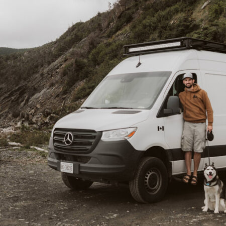 couple posing with dog in front of an RV
