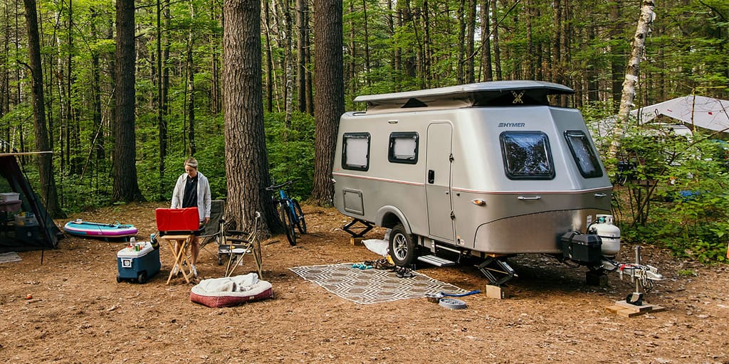 RV and woman cooking over barbeque