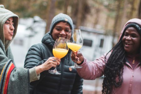 three women from BGOW drinking mimosas while camping in Quebec in their RV