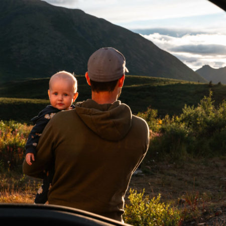 A father holding his newborn daughter looking out into the Yukon wilderness.