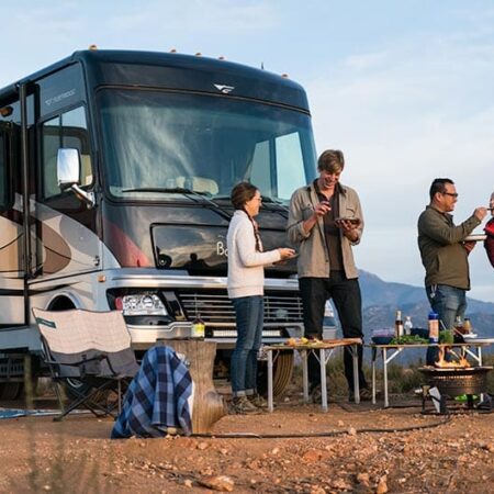 Class A motorhome with group of campers gathered in front