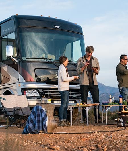 Class A motorhome with group of campers gathered in front