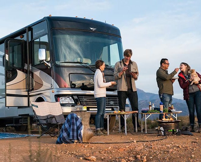 Class A motorhome with group of campers gathered in front