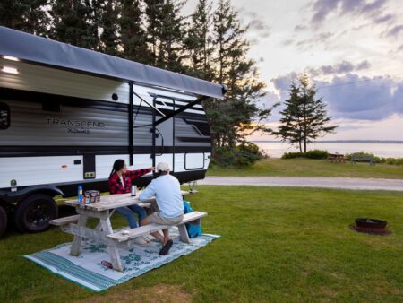 Two campers sitting at a picnic table looking to the ocean