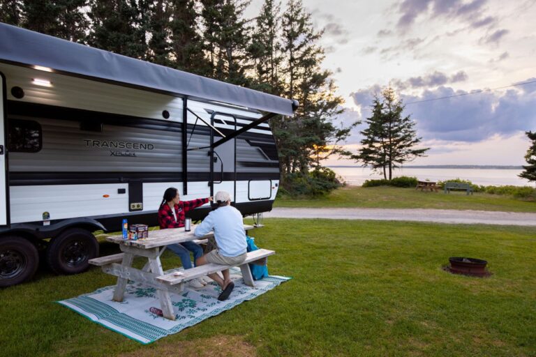 Two campers sitting at a picnic table looking to the ocean