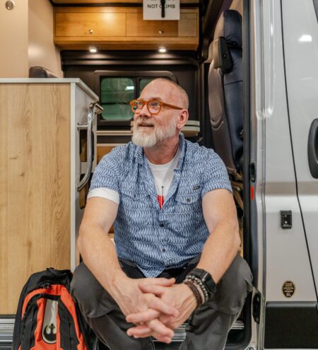 Man sitting at the entrance of his Class B motorhome