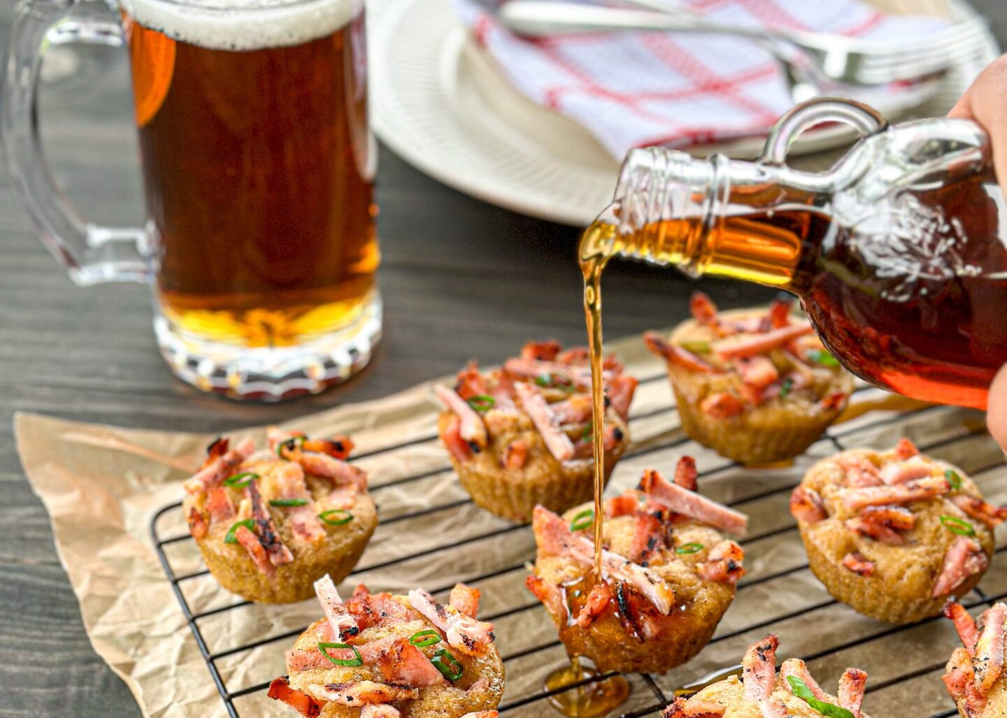 Mini pancakes on a cooling rack with a pint of beer and maple syrup