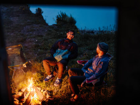 two friends sitting by their campfire camping in their motorhome in Abraham Lake