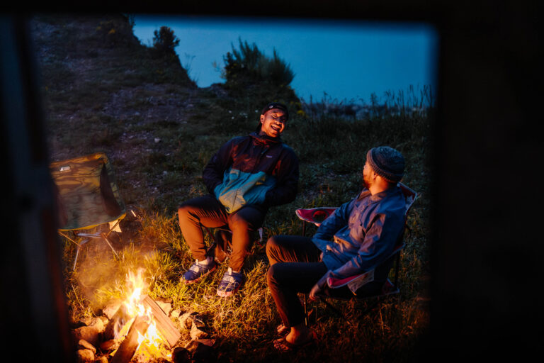 two friends sitting by their campfire camping in their motorhome in Abraham Lake