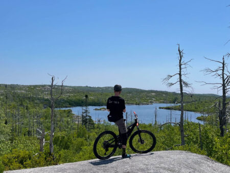 Man resting on the top of a granite rock with his mountain bike on McIntosh Run Nova Scotia