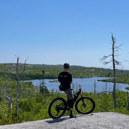 Man resting on the top of a granite rock with his mountain bike on McIntosh Run Nova Scotia