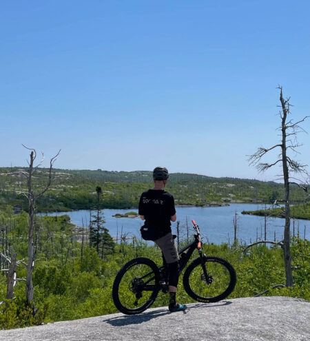 Man resting on the top of a granite rock with his mountain bike on McIntosh Run Nova Scotia