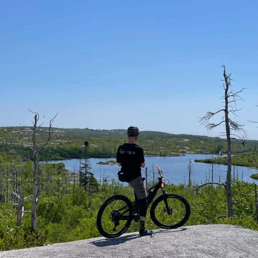 Man resting on the top of a granite rock with his mountain bike on McIntosh Run Nova Scotia