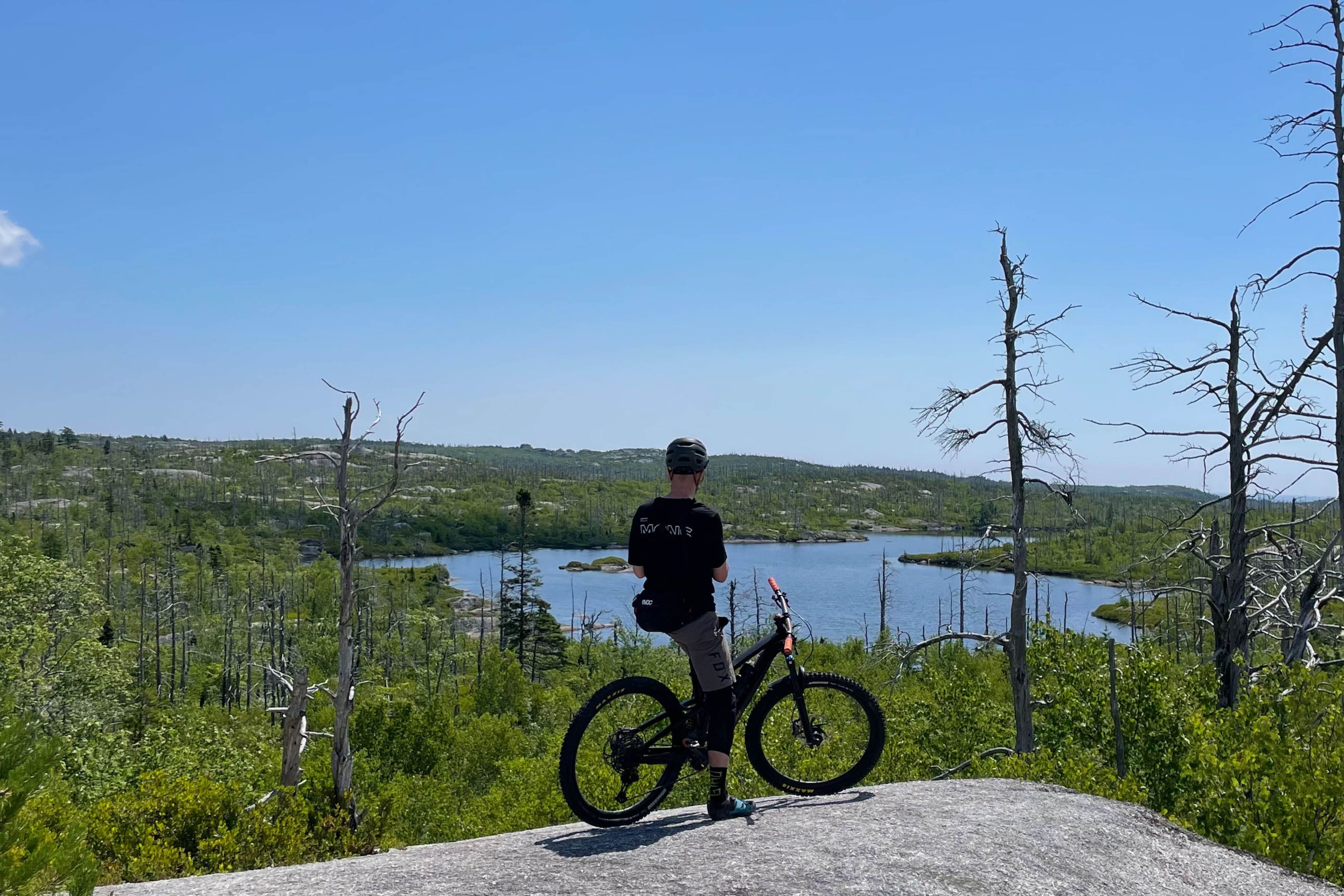 Man resting on the top of a granite rock with his mountain bike on McIntosh Run Nova Scotia