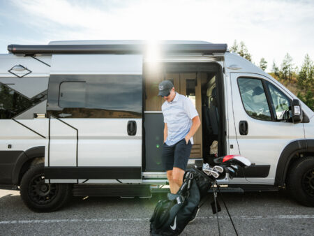 A traveler gets his golf bag out of a camper van in the Revelstoke Golf Club parking lot during a Vernon to Revelstoke RV road trip