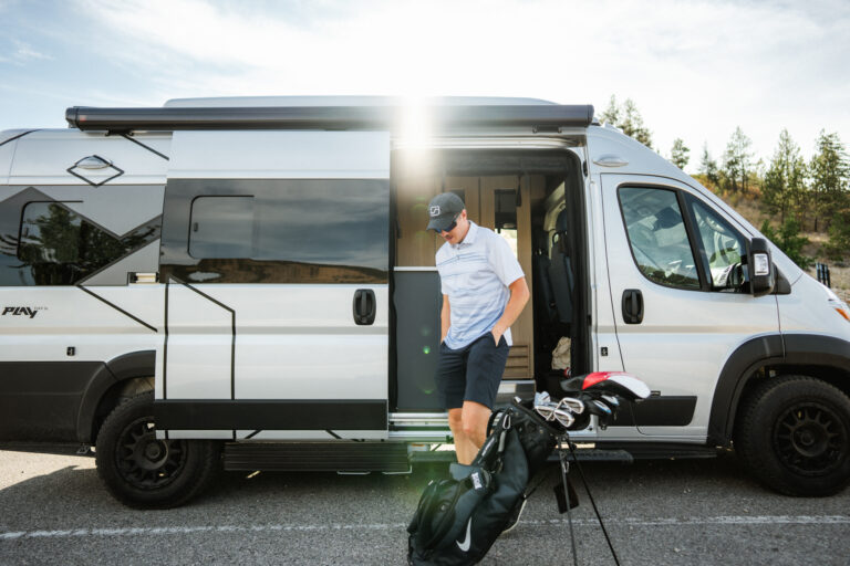 A traveler gets his golf bag out of a camper van in the Revelstoke Golf Club parking lot during a Vernon to Revelstoke RV road trip