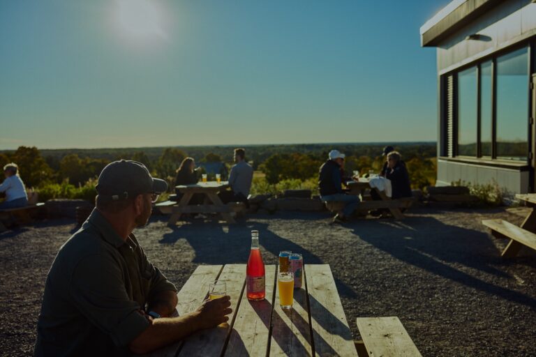 Can of craft beer on the outdoor patio overlooking farm fields at Slake Brewing in Prince Edward County