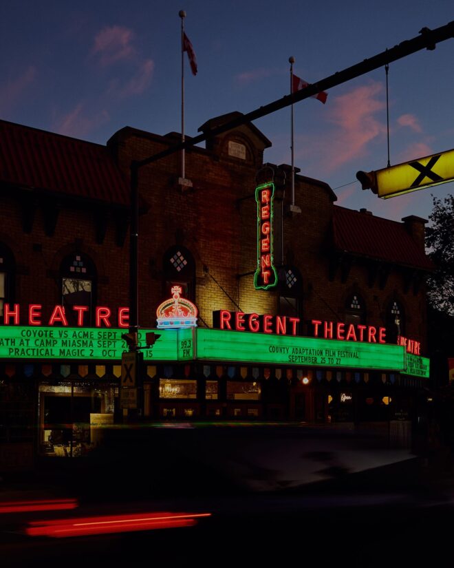Glowing marquee sign of the historic Regent Theatre at night on Main Street in downtown Picton Ontario
