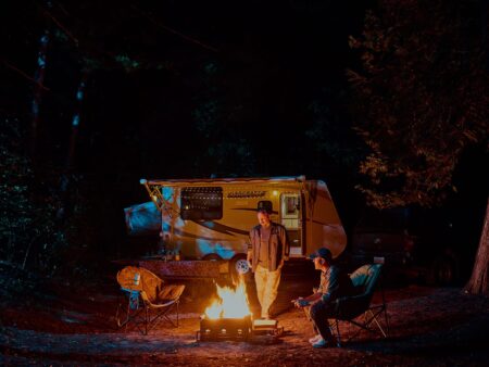 Travel trailer parked at a campsite at Sandbanks Provincial Park with campers sitting around the campfire