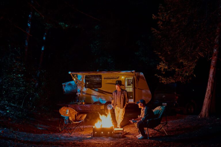 Travel trailer parked at a campsite at Sandbanks Provincial Park with campers sitting around the campfire